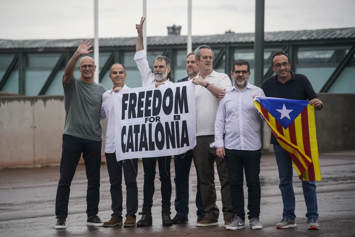 Catalan leaders imprisoned for their role in the 2017 push for an independent Catalan republic, hold a banner and an "estelada" or Catalan pro-independence flag outside Lledoners prison in Sant Joan de Vilatorrada, near Barcelona, Spain, on June 23, 2021. (Joan Mateu/AP)