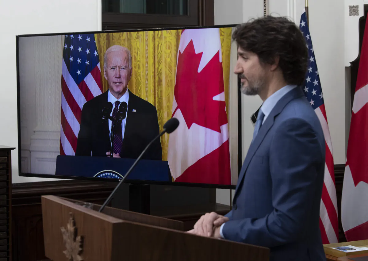 Prime Minister Justin Trudeau looks at a television screen as he listens to U.S. President Joe Biden deliver a statement following a virtual meeting in Ottawa on Feb. 23, 2021. (The Canadian Press/Adrian Wyld)