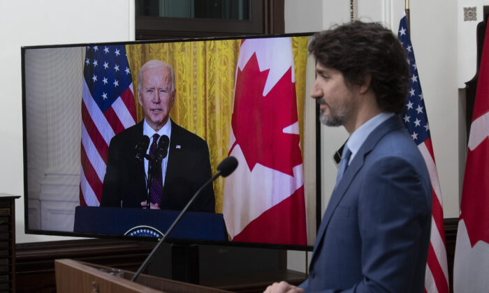 Prime Minister Justin Trudeau looks at a television screen as he listens to U.S. President Joe Biden deliver a statement following a virtual meeting in Ottawa on Feb. 23, 2021. (The Canadian Press/Adrian Wyld)