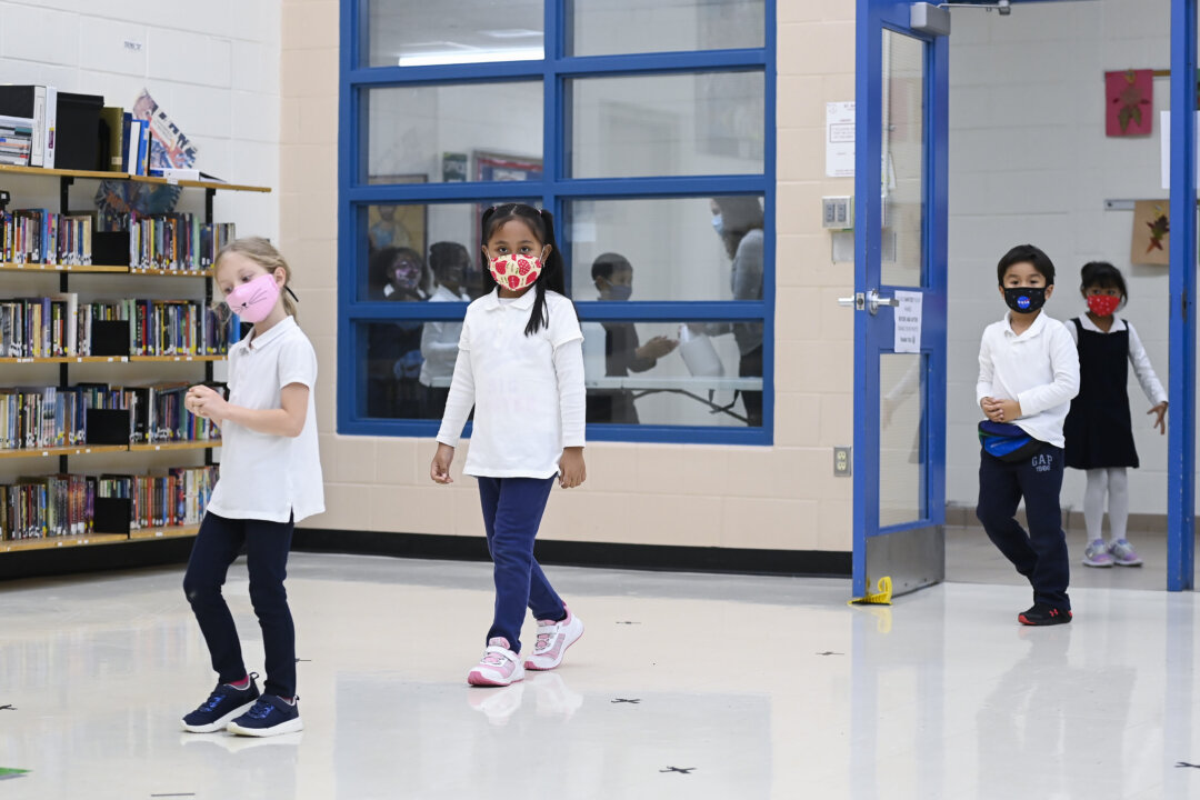 Children arrive in line using physical distancing before getting their picture taken at picture day at St. Barnabas Catholic School during the COVID-19 pandemic in Scarborough, Ont., on Oct. 27, 2020. (THE CANADIAN PRESS/Nathan Denette)