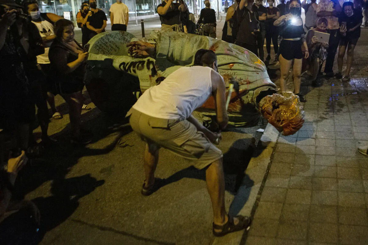 A protester swings a hammer in an attempt to remove the head of the Egerton Ryerson statue after it was toppled at Ryerson University in Toronto on June 6, 2021. (The Canadian Press/Chris Young)