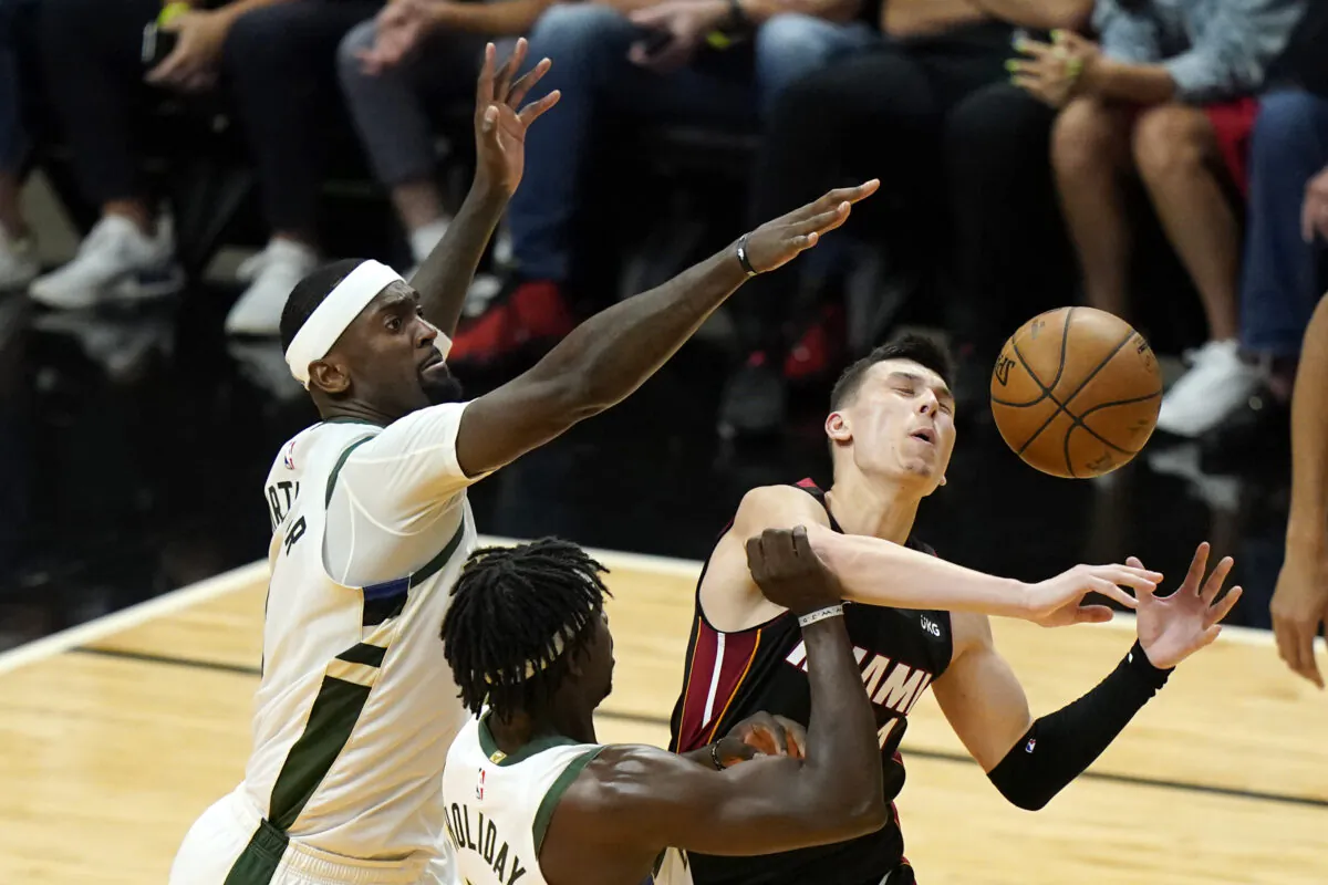 Miami Heat guard Tyler Herro (R) is fouled by Milwaukee Bucks guard Jrue Holiday (C) as center Bobby Portis defends during the second half of Game 4 of an NBA basketball first-round playoff series, in Miami, Fla., on May 29, 2021. (Lynne Sladky/AP Photo)