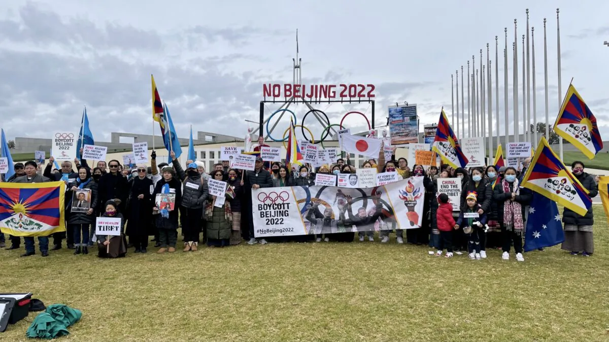 Protesters holds up banners during the “No Beijing 2022” rally outside Parliament House in Canberra, Australia, on June 23, 2021. (The Epoch Times)