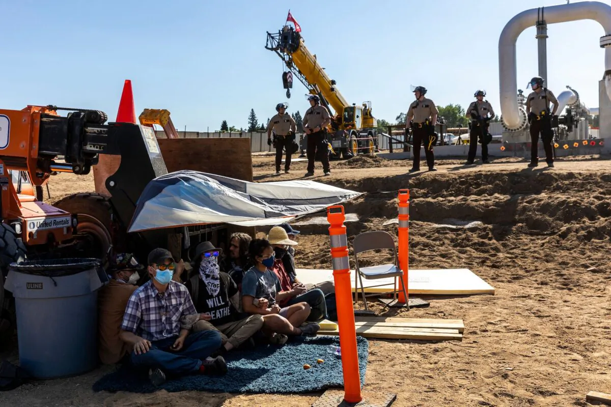 Environmental activists stage a sit-in in front of construction equipment as police stand by, at the Line 3 pipeline pumping station near Itasca State Park, Minn. on June 7, 2021. (Kerem Yucel/Getty Images)