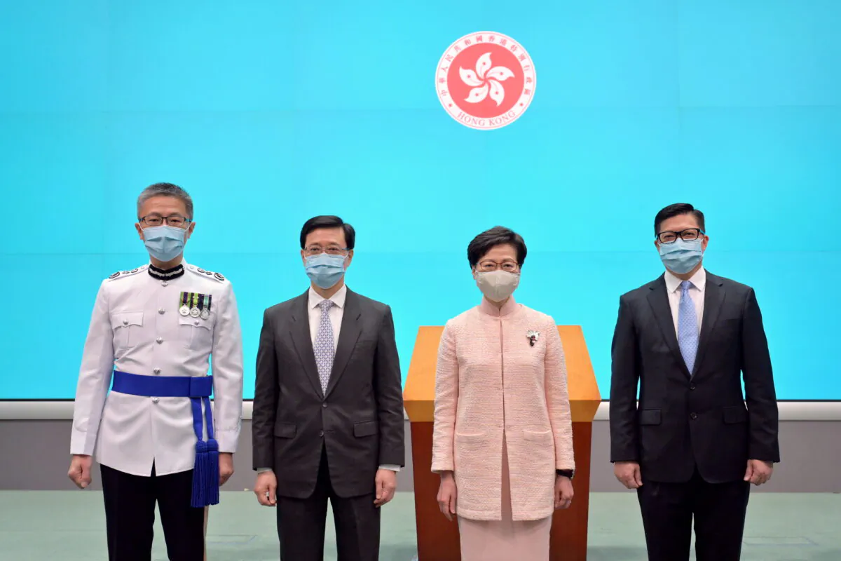(L-R) New Commissioner of Police, Raymond Siu Chak-yee, Chief Secretary for Administration John Lee Ka-chiu and Secretary for Security Chris Tang Ping-keung pose for a photo with Chief Executive Carrie Lam after taking the oath of office in Hong Kong, China June 25, 2021. (Information Services Department/Handout via Reuters)