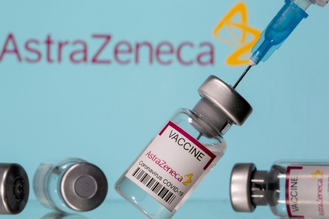 Vials labelled "AstraZeneca COVID-19 Coronavirus Vaccine" and a syringe are seen in front of a displayed AstraZeneca logo, in this illustration photo taken on March 14, 2021. (Dado Ruvic/Illustration/Reuters)
