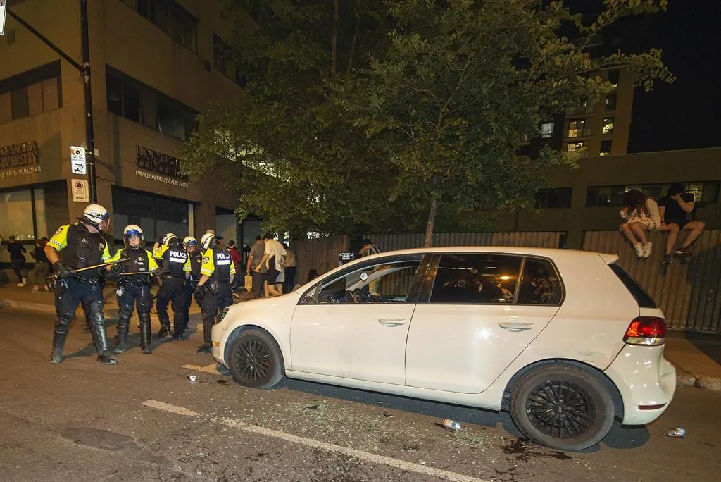 Police surround a car after it was vandalized as Montreal Canadiens fans celebrate on Rue René Lévesque after the Canadiens defeated the Vegas Golden Knights in overtime game 6 NHL Stanley Cup playoff hockey semifinal action in Montreal, on June 24, 2021. (The Canadian Press/Peter McCabe）