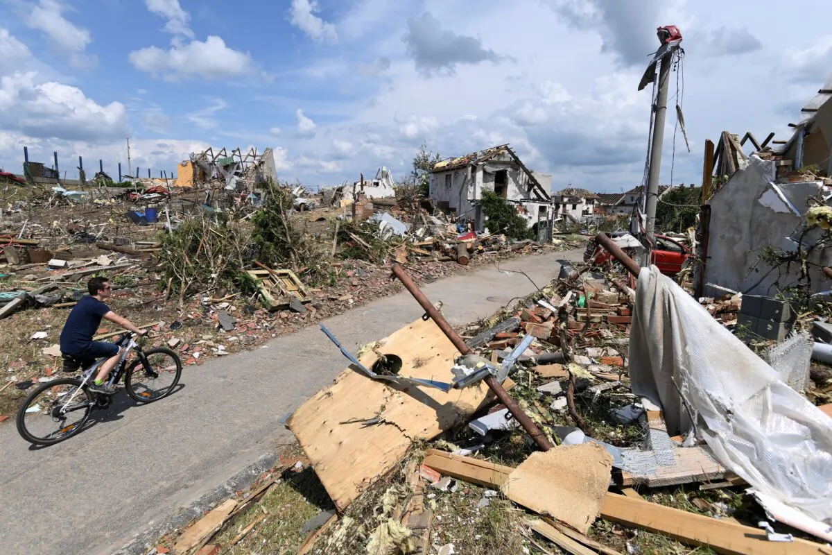 Man rides his bike after a tornado hit the village of Mikulcice in the Hodonin district, South Moravia, Czech Republic, on June 25, 2021. (Ondrej Deml/CTK via AP)