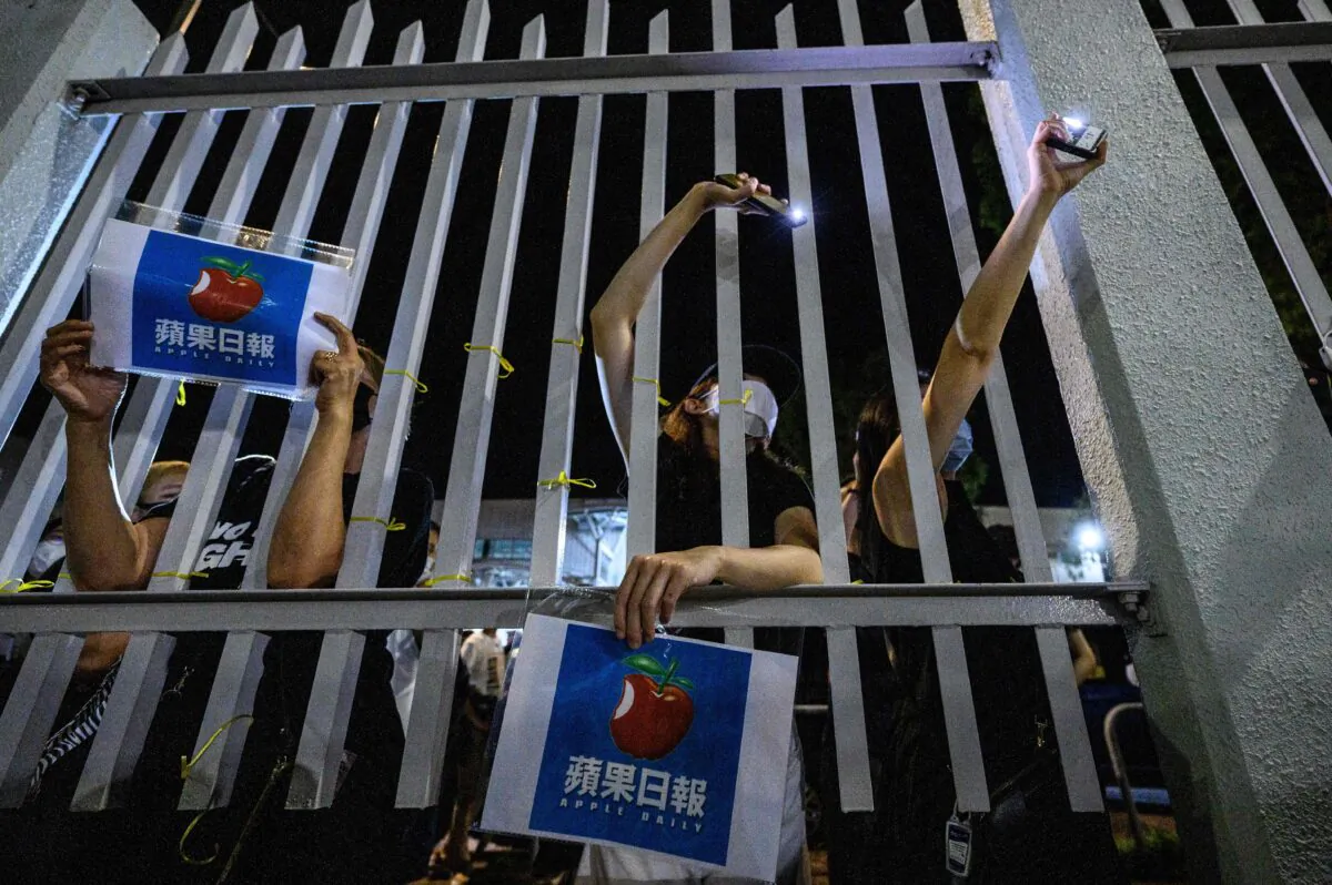 Supporters stand outside the main gate of the Apple Daily offices after the company's final newspapers were printed at the printing facility in Hong Kong early on June 24, 2021. (Anthony Wallace/AFP via Getty Images)