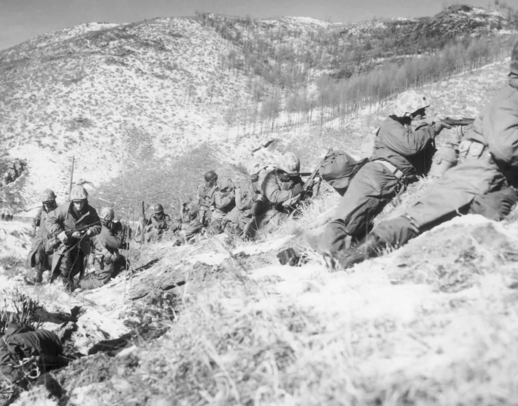 United States Marines infantrymen, taking cover behind large boulders, shoot at North Korean forces during a battle on a snow-covered mountain in the Korean War, Korea, on Dec. 6, 1950. The Marines won the battle, backed by close air support. (Hulton Archive/Getty Images)