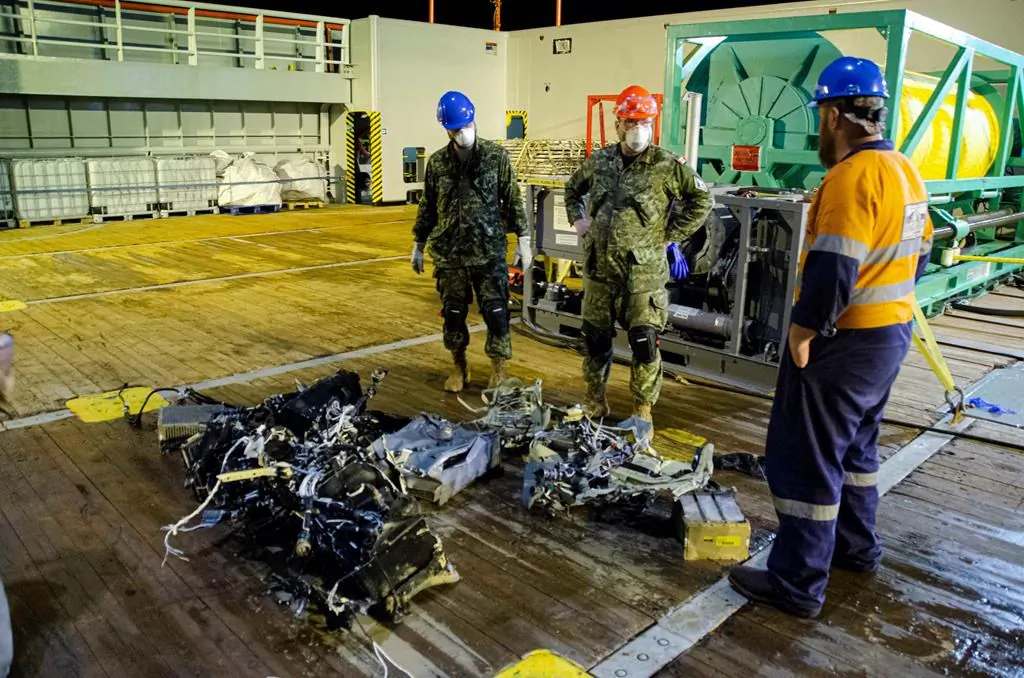 Canadian Forces members and EDT Hercules personnel inspect recovered parts of the helicopter Stalker 22 during recovery operations for the aircraft in the Mediterranean Sea on May 31, 2020. (The Canadian Press/HO-Department of National Defence, Cdr Robert Watt)