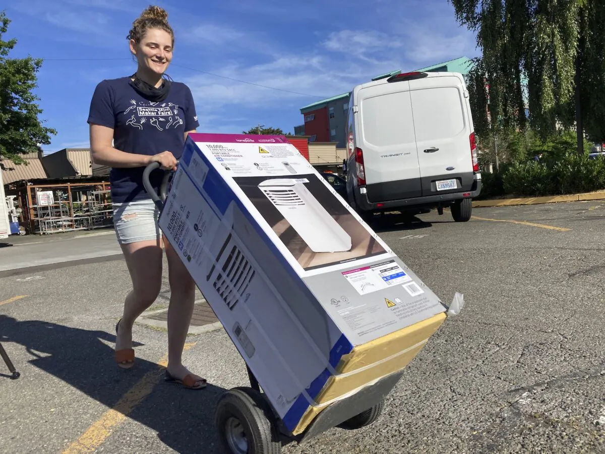 Sarah O'Sell transports her new air conditioning unit to her nearby apartment on a dolly in Seattle, Wash., on June 25, 2021. (Manuel Valdes/AP Photo)