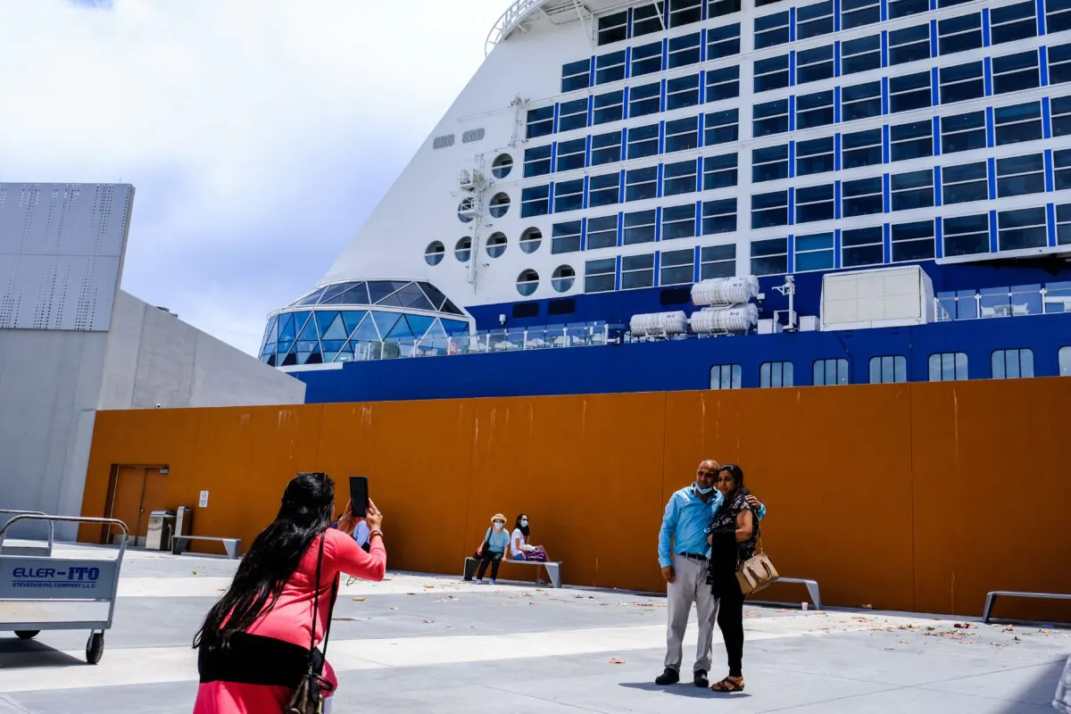 A woman takes a photo of a couple before the Celebrity Edge cruise ship in Fort Lauderdale, Fla., on June 26, 2021. (Maria Alejandra/AFP via Getty Images)