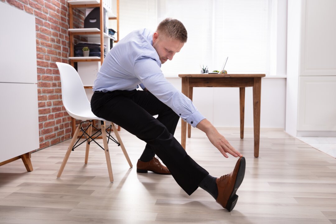Chair stretching can include reaching for the sky with both arms, breathing, and twisting by turning your head to the right and torso to left. (Andrey_Popov/Shutterstock)