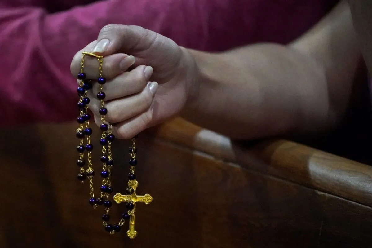 A young woman holds a rosary as she prays during a prayer vigil in Miami Beach, Fla., on June 26, 2021. (Wilfredo Lee/AP Photo)