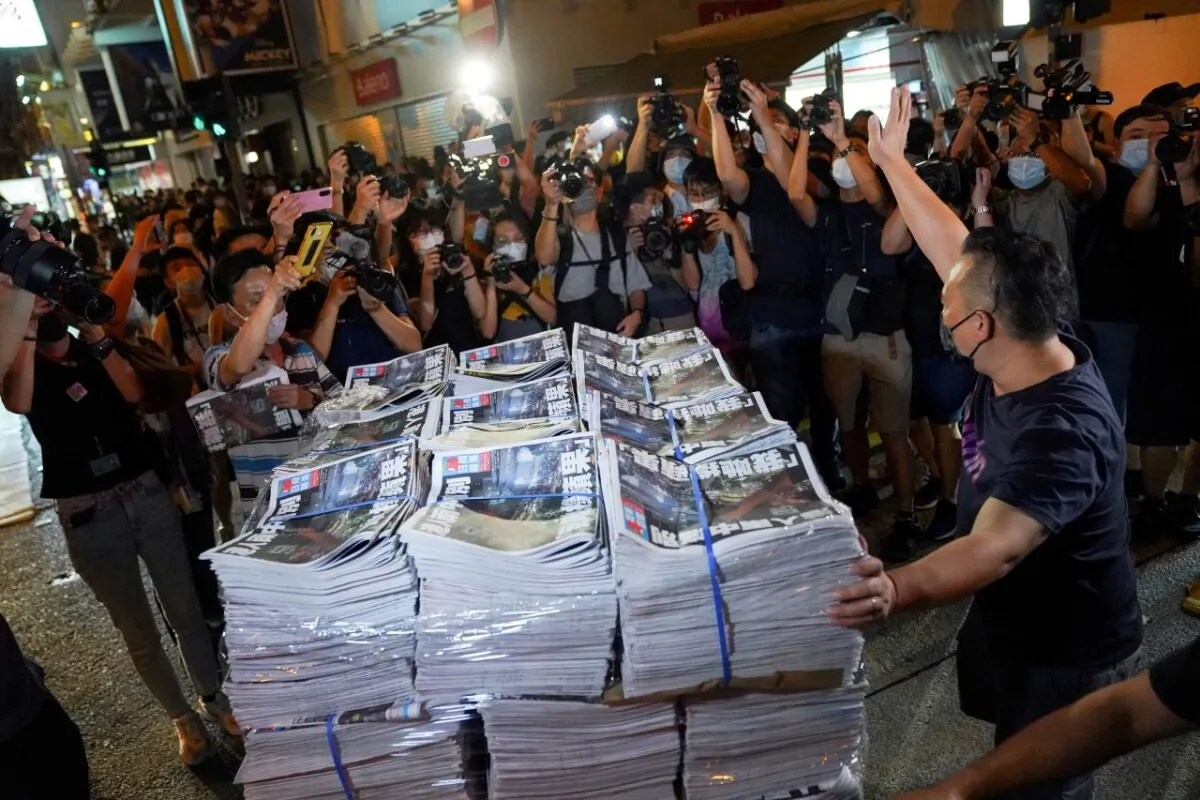 A man gestures as he brings copies of the final edition of Apple Daily, published by Next Digital, to a news stand in Hong Kong, China, on June 24, 2021. (Lam Yik/Reuters)