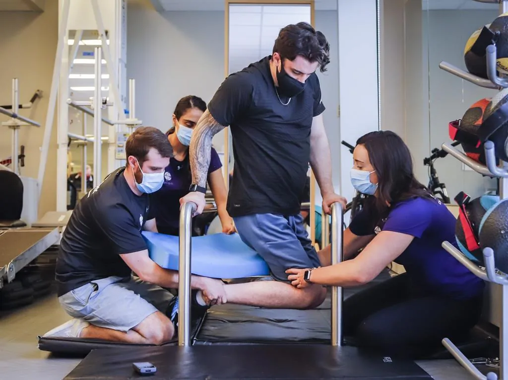 Humboldt Broncos bus crash survivor Ryan Straschnitzki, centre, is helped to turn his body by Eric Daigle, left, and Jill Mack while he attends a physiotherapy session in Calgary, Alta., June 24, 2021. (The Canadian Press/Jeff McIntosh)