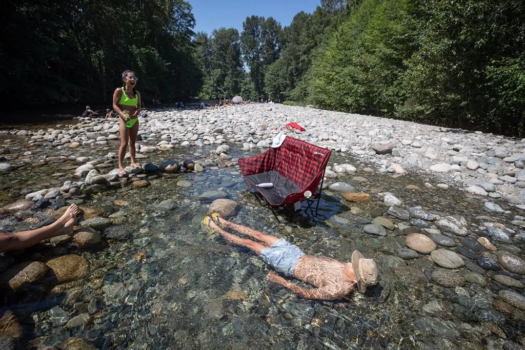 A man cools off in the frigid water of Lynn Creek in North Vancouver on June 28, 2021. (The Canadian Press/Darryl Dyck)