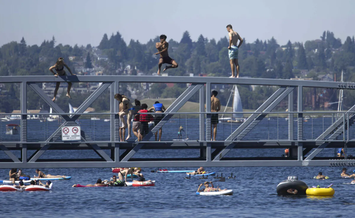 Two people jump from a pedestrian bridge at Lake Union Park into the water during a heat wave hitting the Pacific Northwest, on June 27, 2021. (John Froschauer/AP Photo)