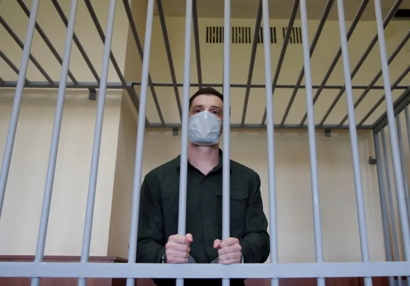 Former U.S. Marine Trevor Reed stands inside a defendants' cage during a court hearing in Moscow, Russia, on July 30, 2020. (Maxim Shemetov/Reuters)