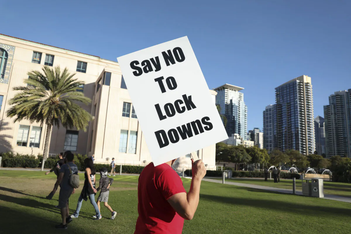 A man holds a sign opposing a lock-down during a rally at the County Administration Building, in San Diego, Calif., on Nov. 16, 2020. (Sandy Huffaker/Getty Images)