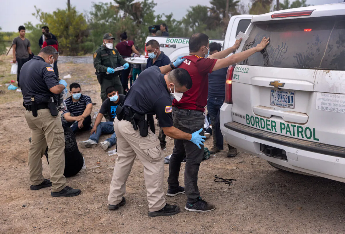 A transport officer searches immigrants before bussing them to a processing center after they crossed the border from Mexico in La Joya, Texas, on April 13, 2021. (John Moore/Getty Images)