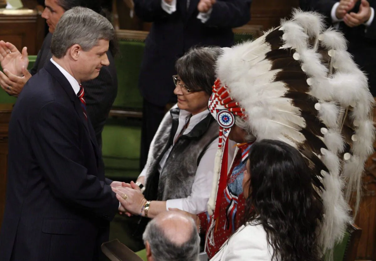 Inuit Tapiriit Kanatami President Mary Simon shakes hands with Prime Minister Stephen Harper, as Assembly of First Nations Chief Phil Fontaine watches, after the government's official apology for residential schools, in the House of Commons on June 11, 2008. (The Canadian Press/Fred Chartrand)