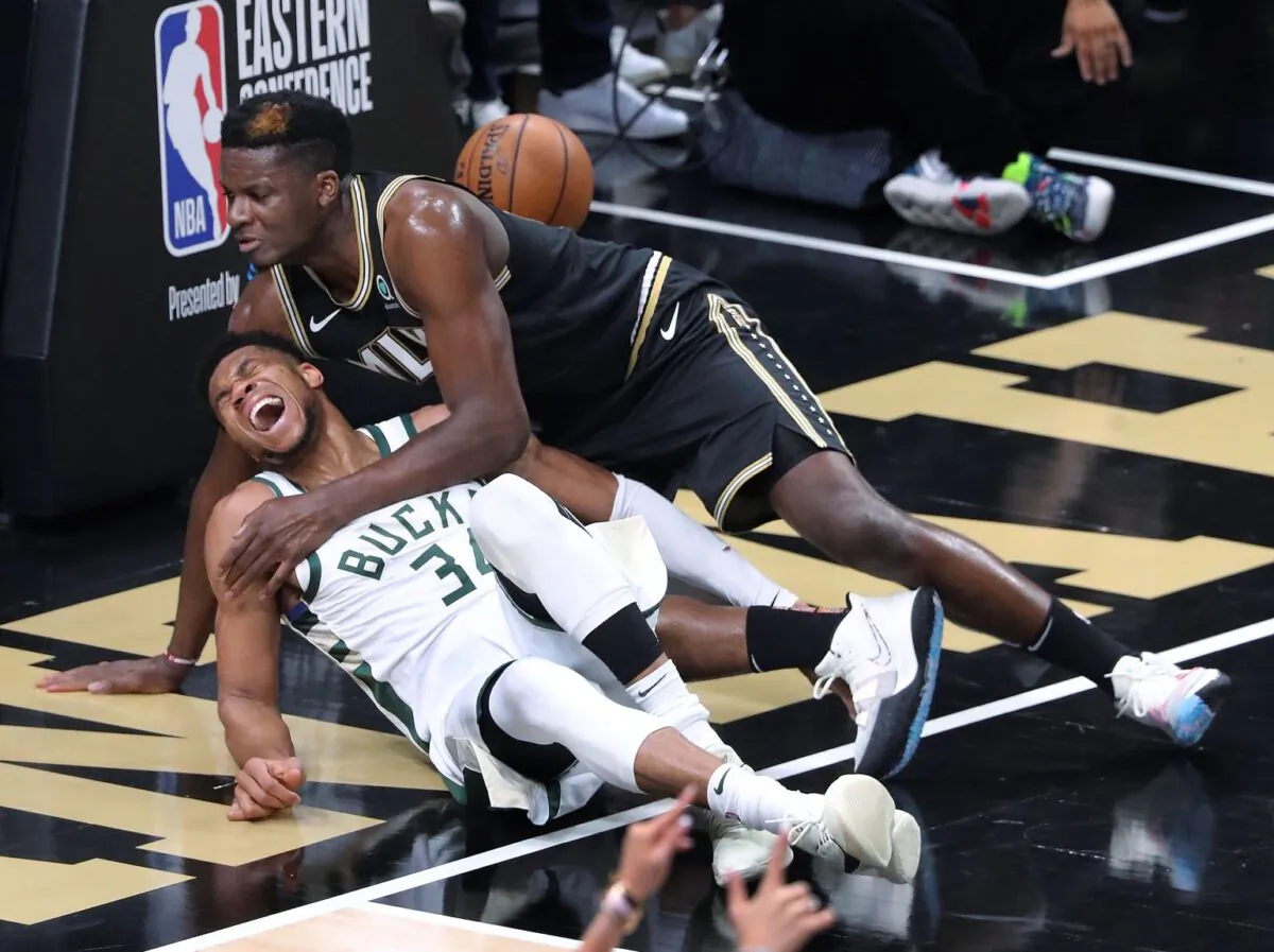Atlanta Hawks center Clint Capela (T) and Milwaukee Bucks forward Giannis Antetokounmpo fall to the court during the third quarter in Game 4 of the Eastern Conference finals in the NBA basketball playoffs in Atlanta, on June 29, 2021. (Curtis Compton/Atlanta Journal-Constitution via AP)