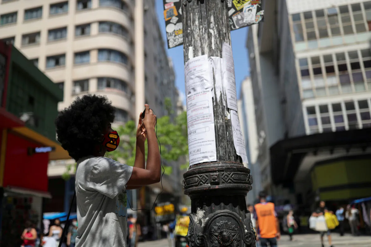 A woman photographs with her phone a job opportunity on job listings posted on a light pole in downtown Sao Paulo, Brazil, on Sept. 30, 2020. (Amanda Perobelli/Reuters)