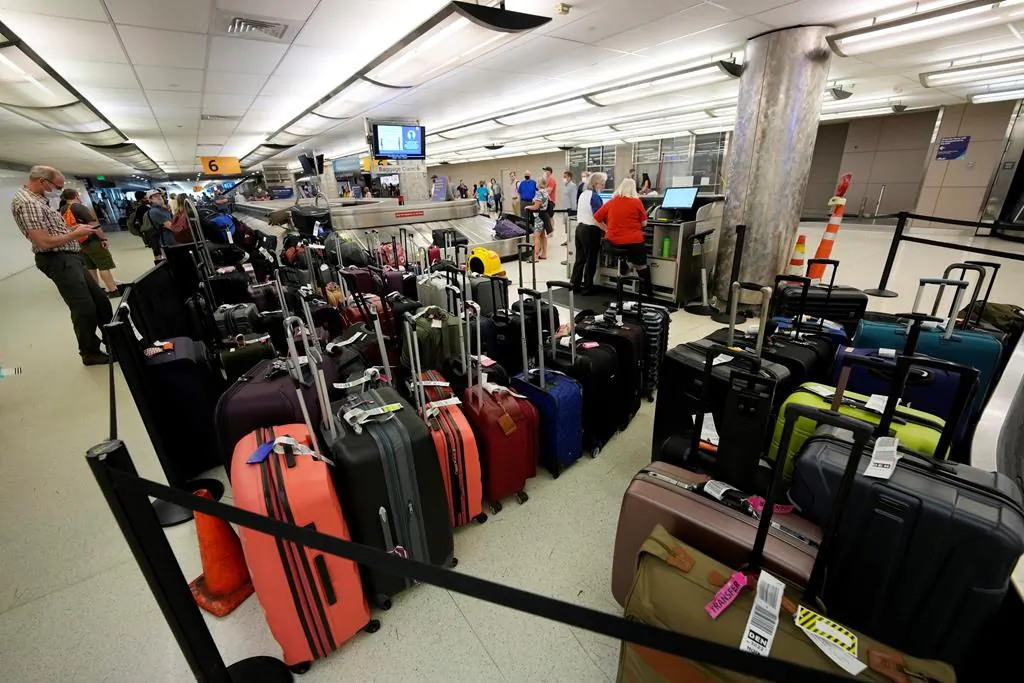Baggage stacks up from delayed travellers in the baggage claim area in Denver International Airport on June 16, 2021, in Denver. (AP Photo/David Zalubowski)