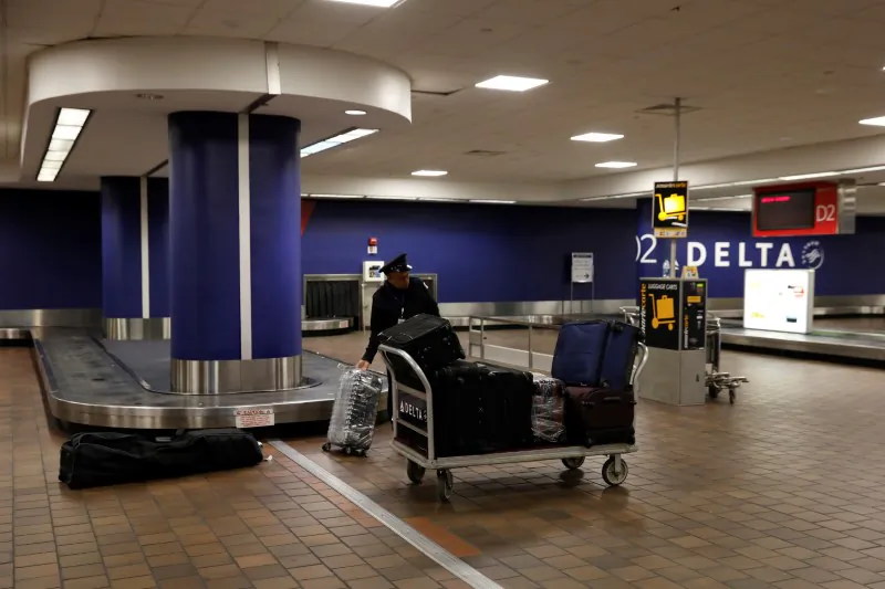A baggage claim employee grabs bags from an empty baggage claim area in Delta terminal at LaGuardia Airport in New York, on March 21, 2018. (Shannon Stapleton/Reuters)