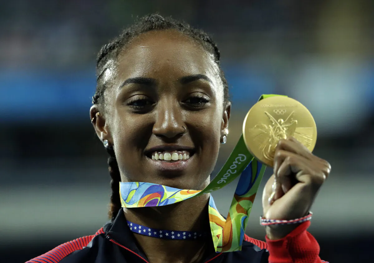 Gold medal winner Brianna Rollins from the United States shows off her medal during the medal ceremony for the women's 100-meter hurdles final, at the Olympic stadium in Rio de Janeiro, Brazil. Thursday, Aug. 18, 2016. (Dmitri Lovetsky/AP Photo)