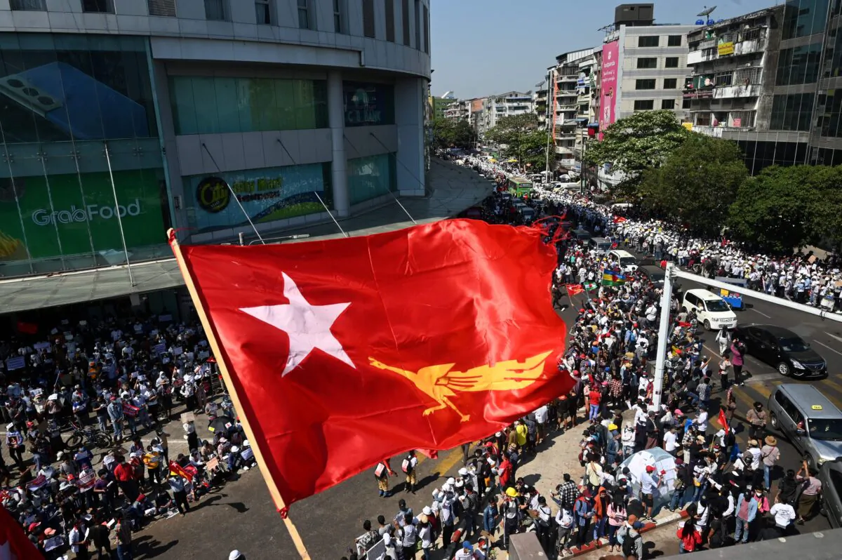 The flag of the National League for Democracy party flies over protesters taking part in a demonstration against the February 1 military coup in Yangon on February 10, 2021. (Sai Aung Main/AFP via Getty Images)