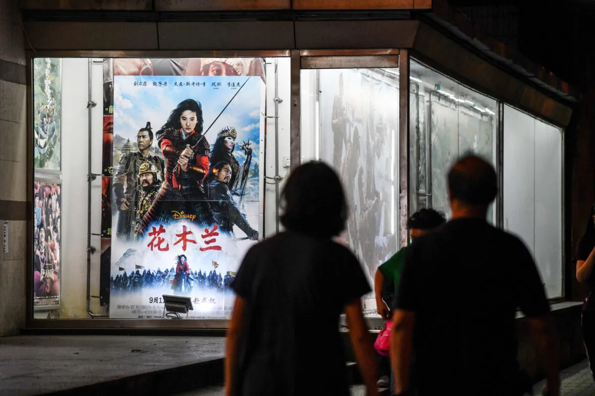 People walk past a poster of the Disney movie 'Mulan' outside a cinema in Beijing on Sept. 10, 2020. (Greg Baker/AFP via Getty Images)