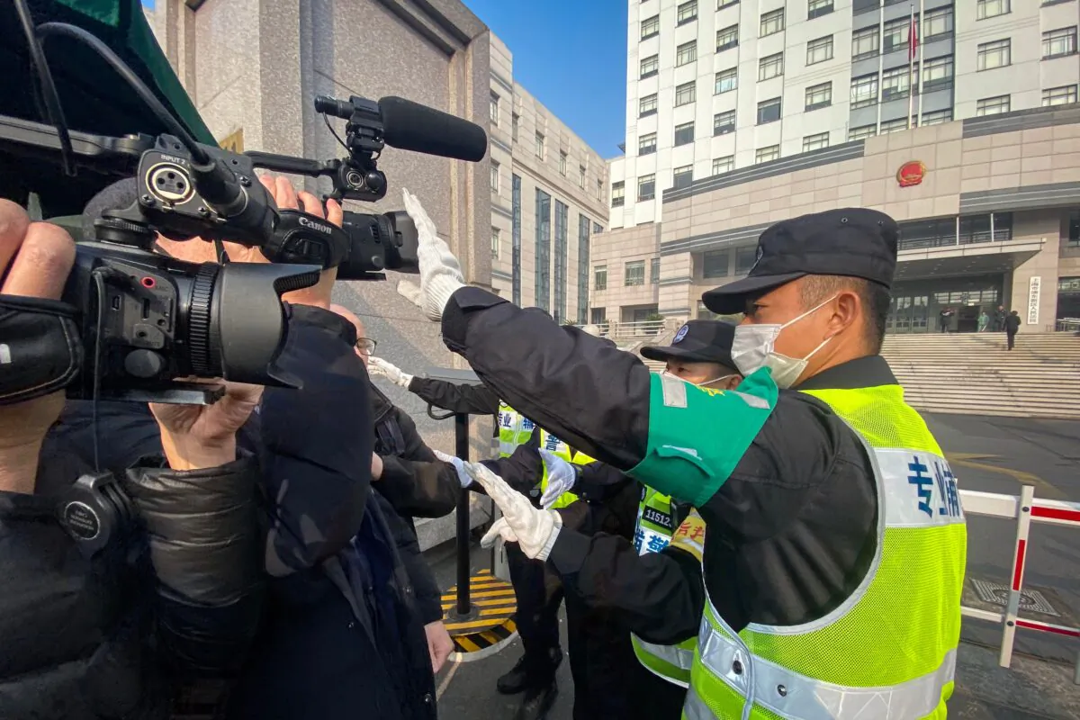 A policeman covers a camera to stop a journalist from recording footage outside the Shanghai Pudong New District People's Court in Shanghai, China, on December 28, 2020. (Leo Ramirez/AFP via Getty Images)