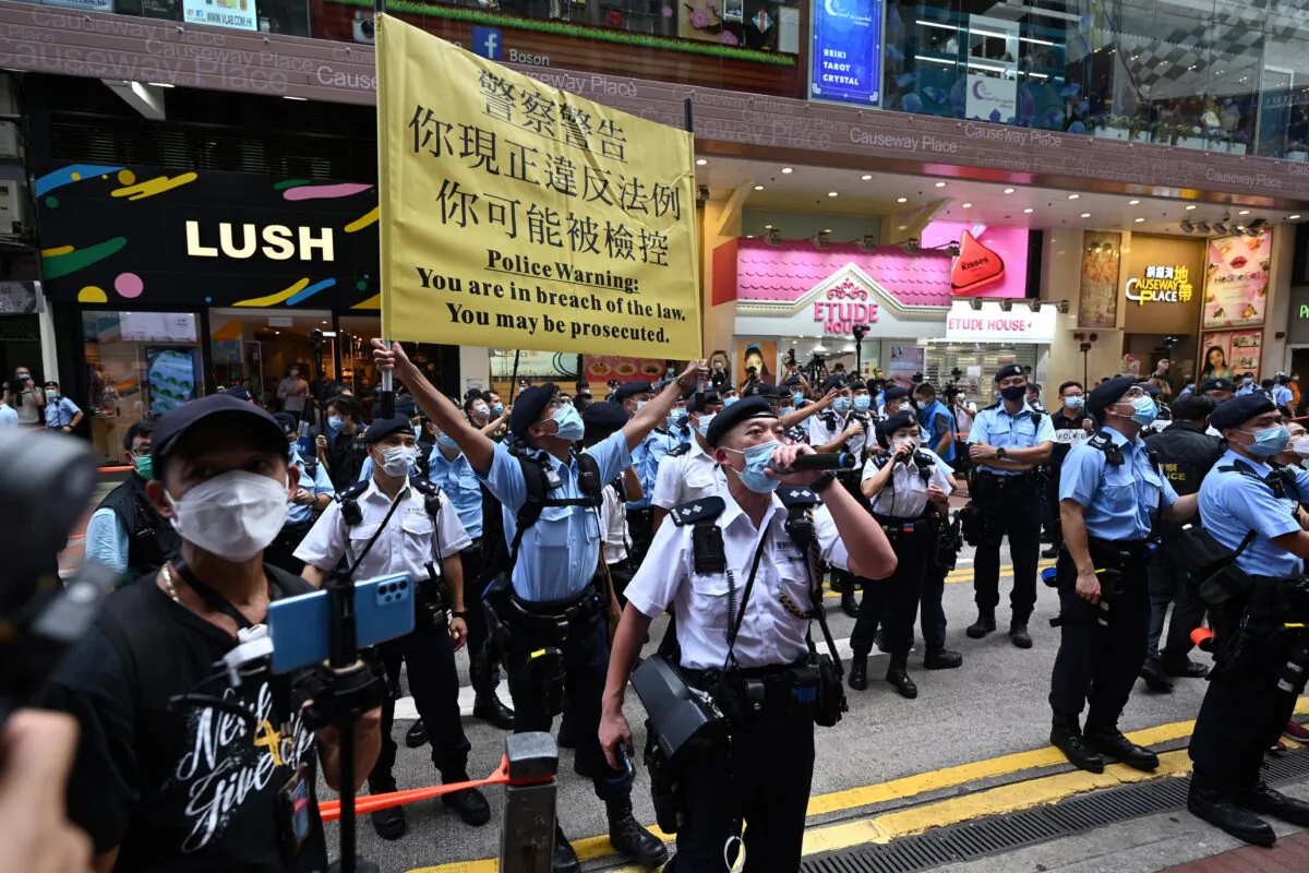Police hold up a warning banner and instruct people to move on during the 24th anniversary of Hong Kong's handover from Britain to Chinese rule in Hong Kong on July 1, 2021. (Peter Parks/AFP via Getty Images)