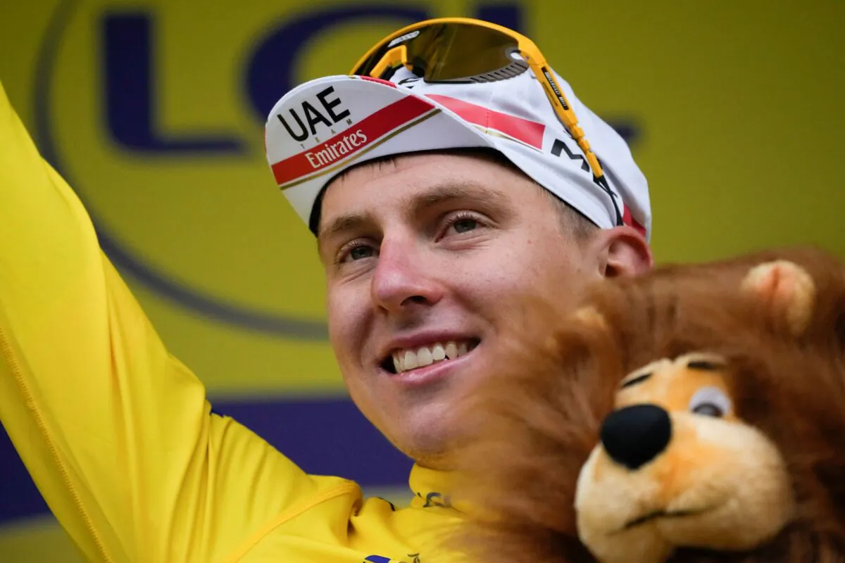 Slovenia's Tadej Pogacar, wearing the overall leader's yellow jersey, celebrates on the podium after the eighth stage of the Tour de France cycling race over 150.8 kilometers (93.7 miles) with start in Oyonnax and finish in Le Grand-Bornand, France, on July 3, 2021. (Christophe Ena/AP Photo)