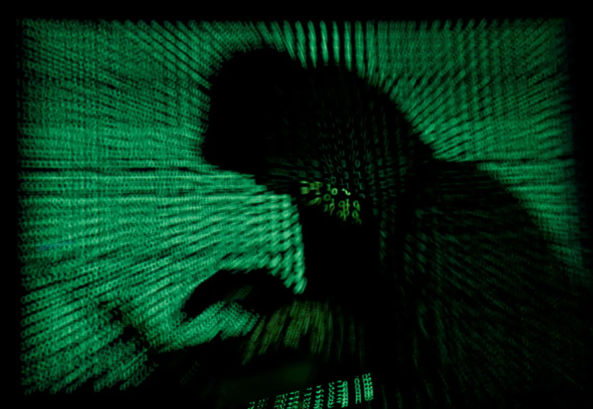 A hooded man holds a laptop computer as cyber code is projected on him in this illustration picture, May 13, 2017.  (Kacper Pempel/Illustration/File Photo/Reuters)