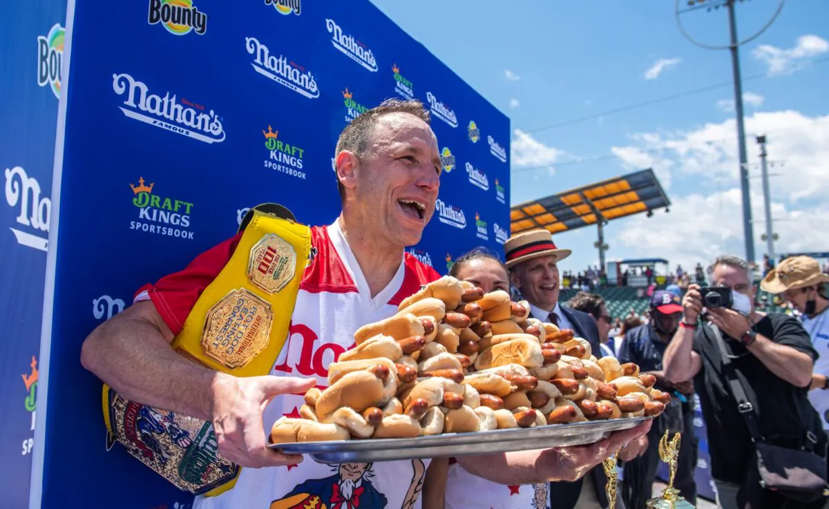 Winners Joey Chestnut and Michelle Lesco, obscured behind hot dogs, pose at the Nathan's Famous Fourth of July International Hot Dog-Eating Contest in Coney Island's Maimonides Park in the Brooklyn borough of New York City, on July 4, 2021. (Brittainy Newman/AP Photo)