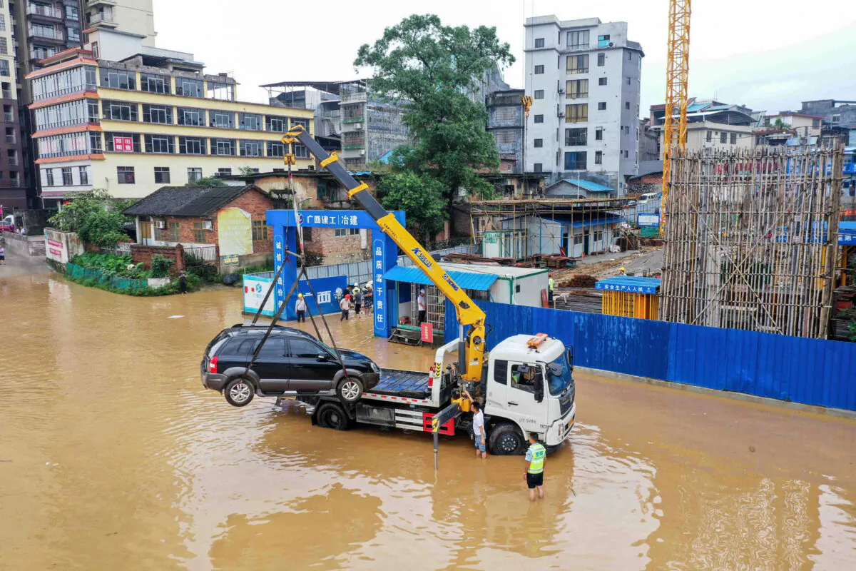 A crane lifts a car on a flooded street near the swollen Rongjiang river after heavy rains in Rongan, in China's southern Guangxi region on July 2, 2021. - China OUT (Photo by STR / AFP) / China OUT (Photo by STR/AFP via Getty Images)