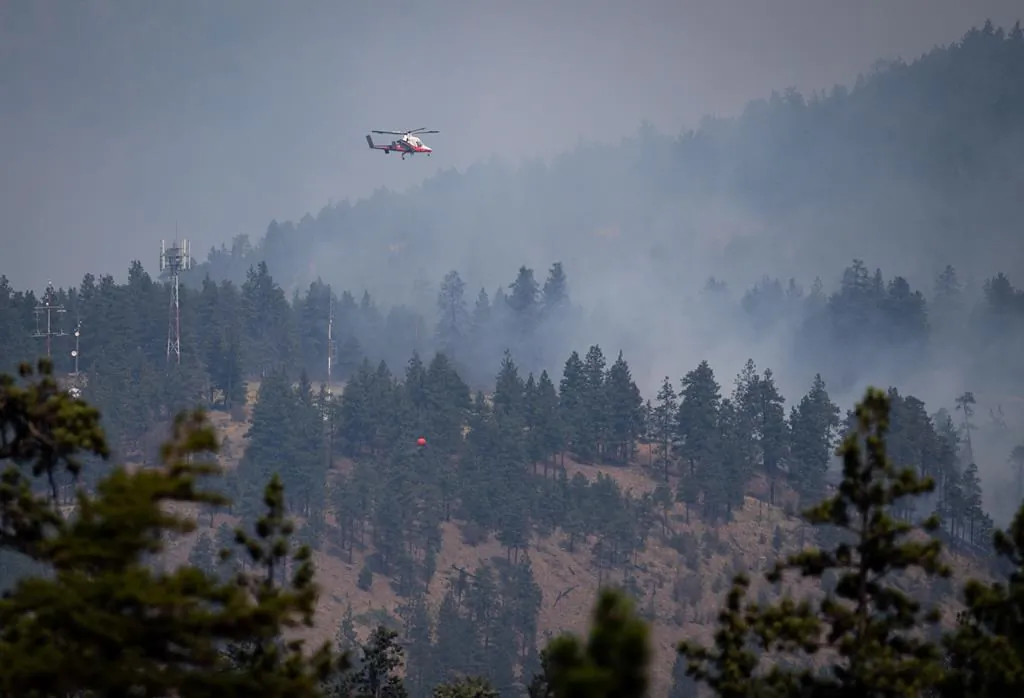 A helicopter pilot prepares to drop water on a wildfire burning in Lytton, B.C., on July 2, 2021. (The Canadian Press/Darryl Dyck)