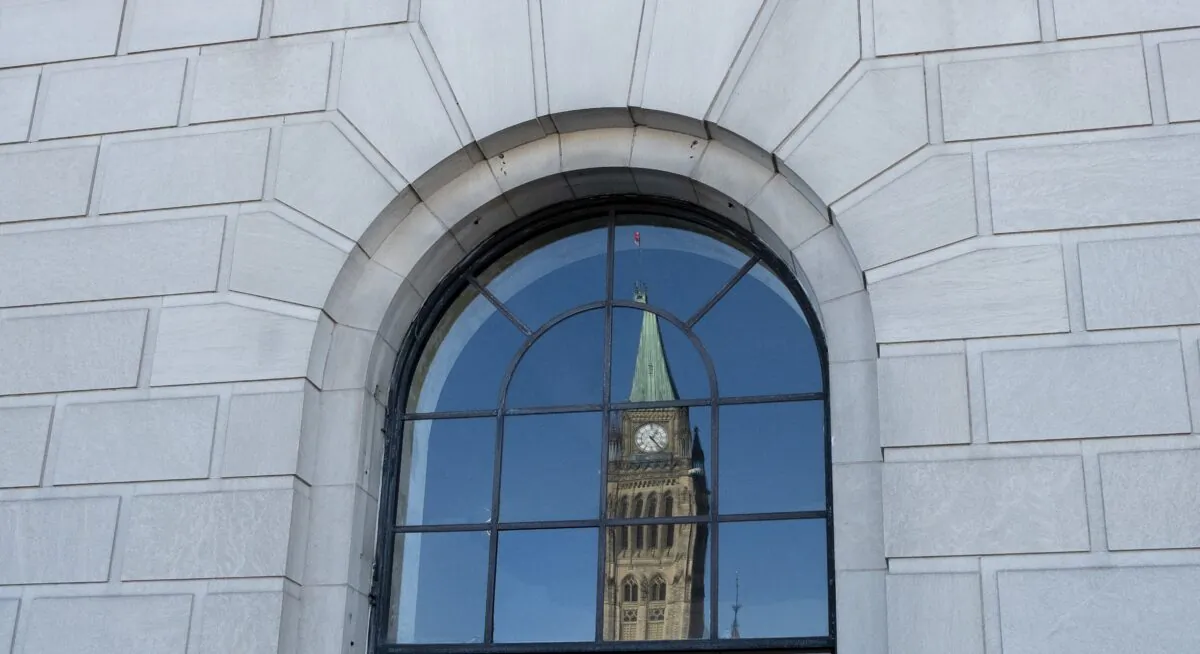 The Peace Tower on Parliament Hill is reflected in a window in downtown Ottawa on March 26, 2019. (The Canadian Press/Adrian Wyld)