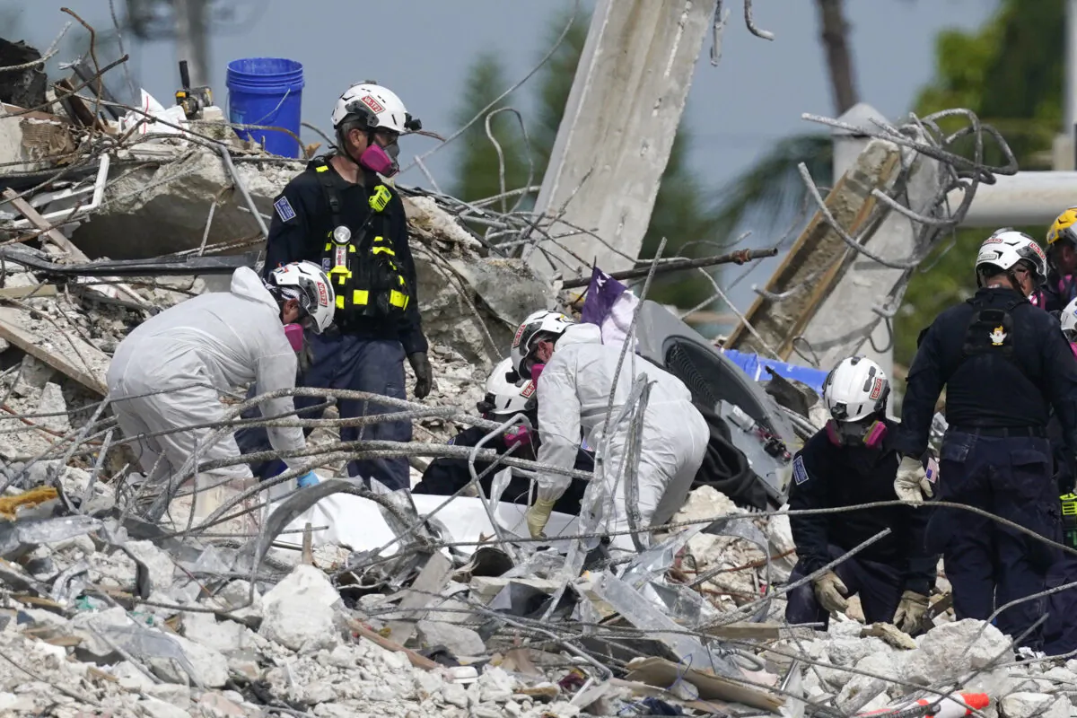 Search and rescue team members climb the rubble of the Champlain Towers South condo in Surfside, Fla., on July 7, 2021. (Al Diaz/Miami Herald via AP)