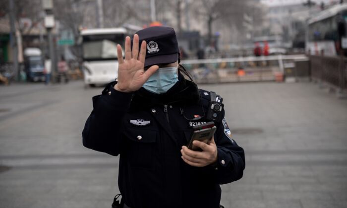 A police officer gestures to a journalist not to photograph in Beijing, China, on March 5, 2021. (NICOLAS ASFOURI/AFP via Getty Images)