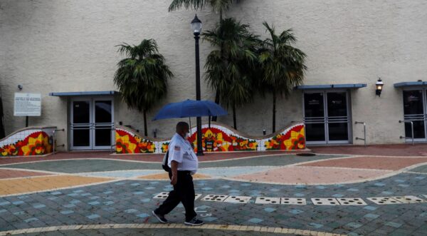A man walks with an umbrella ahead of Tropical Storm Elsa