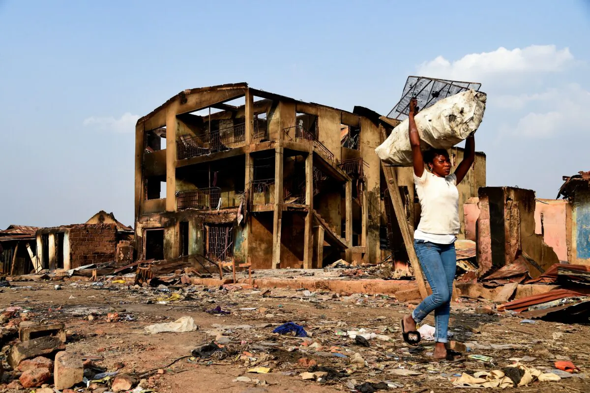 A woman carries wares recovered from burned shops as she walks past a three-story building burned during deadly clashes with the northern Fulani at Shasha Market in Ibadan, southwest Nigeria, on Feb. 15, 2021. (Pius Utomi Ekpei/AFP via Getty Images)