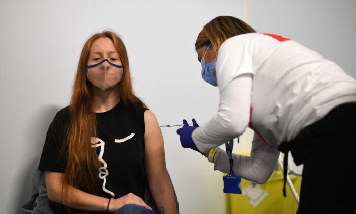 Members of the public receive a dose of a COVID-19 Pfizer vaccine inside a temporary vaccination center set up at the Emirates Stadium, home to the Arsenal football club, in north London on June 25, 2021. (Daniel Leal-Olivas/AFP via Getty Images)