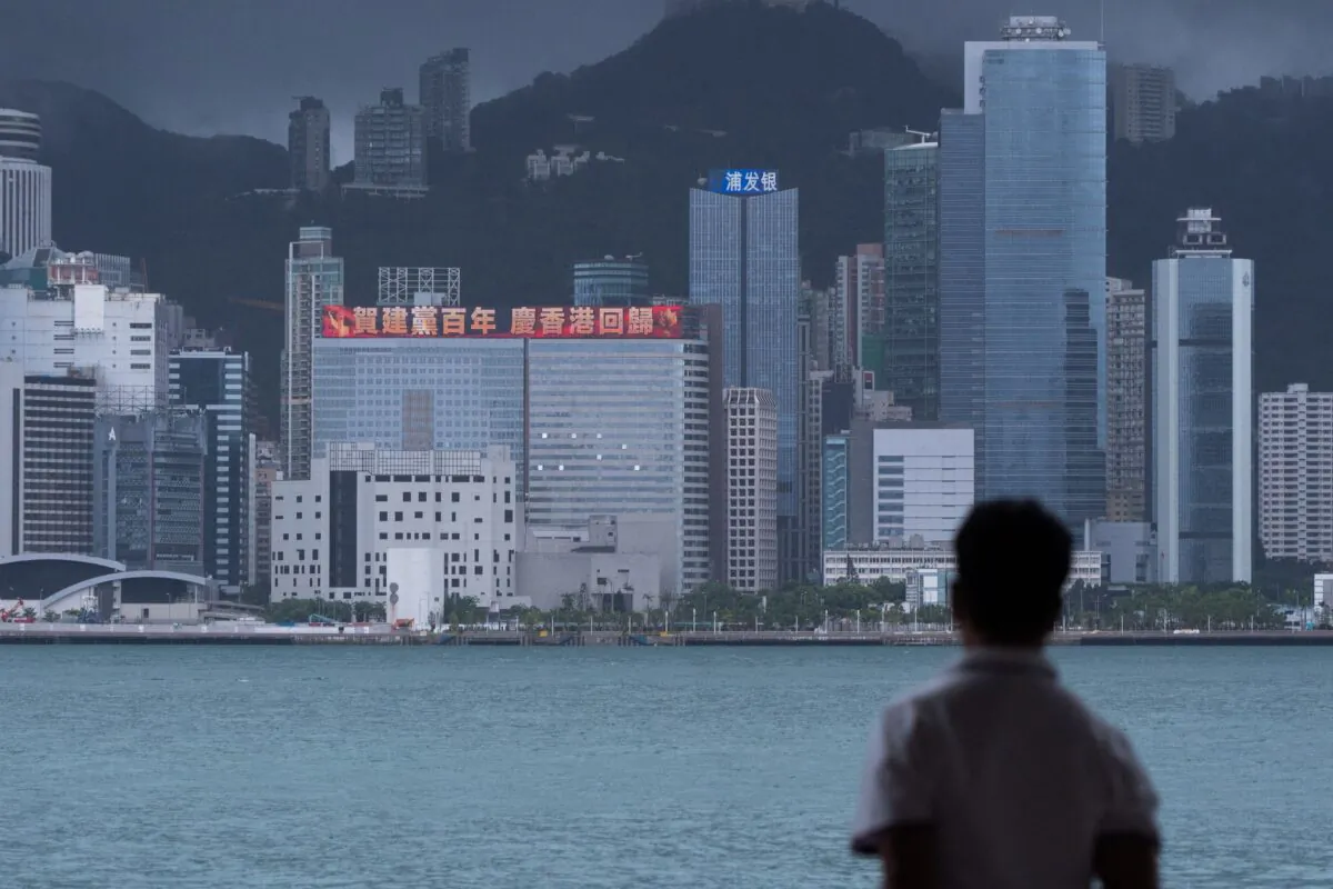 A man looks at a building with an LED billboard displaying a slogan celebrating the 100th anniversary of the Chinese Communist Party and the 24th anniversary of Hong Kong's return to China in Hong Kong, on June 29, 2021. (Bertha Wang/AFP via Getty Images)