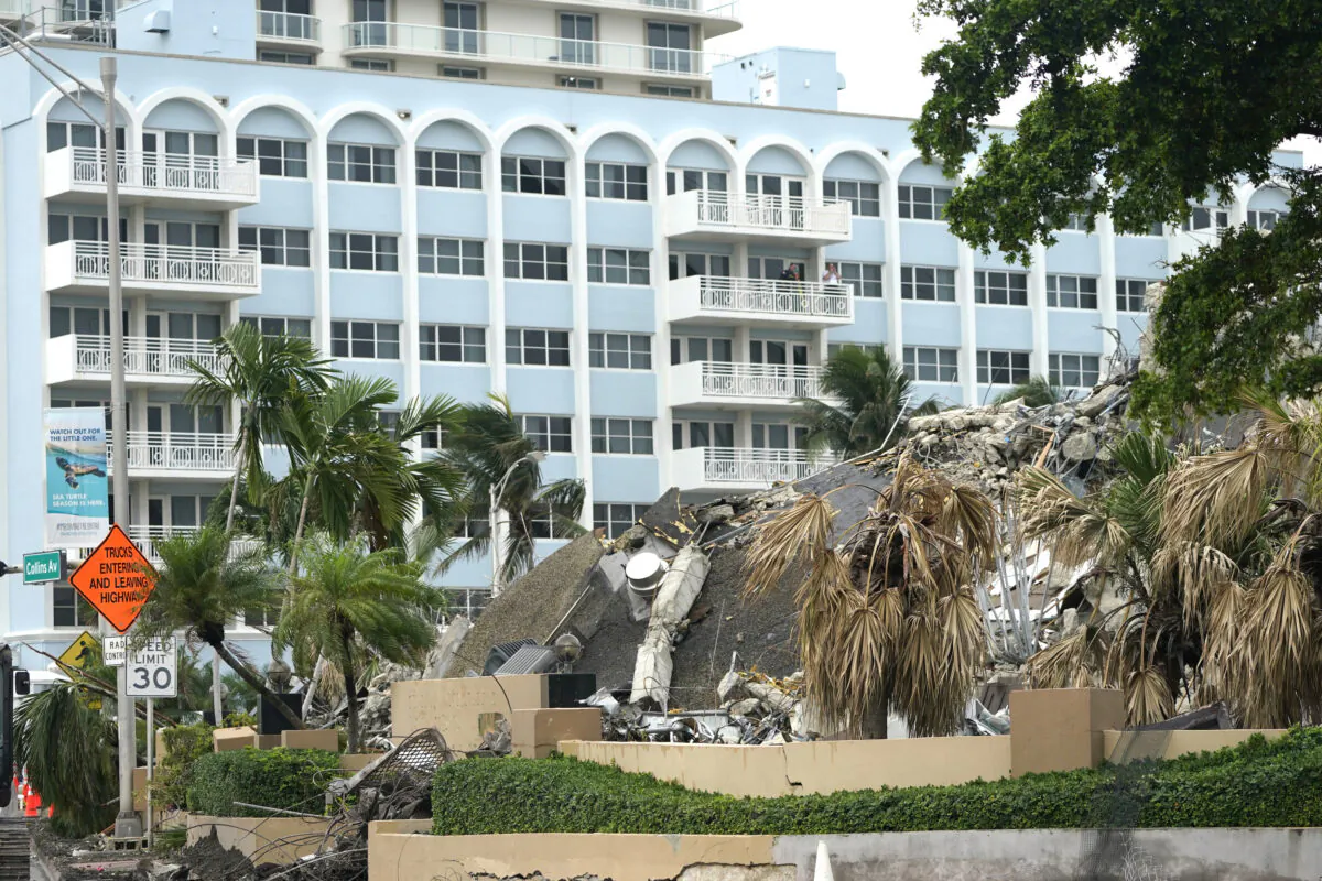 People look out from a balcony onto the collapsed and subsequently demolished Champlain Towers South condominium building in Surfside, Fla., on July 6, 2021. (Lynne Sladky/AP Photo)