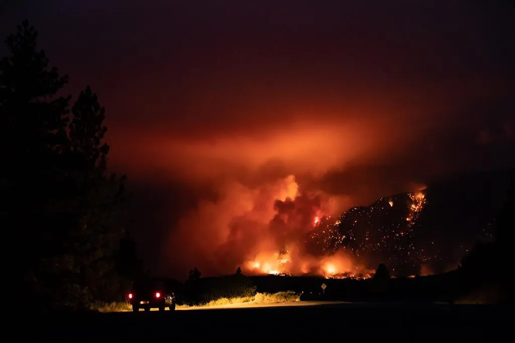 A motorist watches from a pullout on the Trans-Canada Highway as a wildfire burns on the side of a mountain in Lytton, B.C., on July 1, 2021. (The Canadian Press/Darryl Dyck)